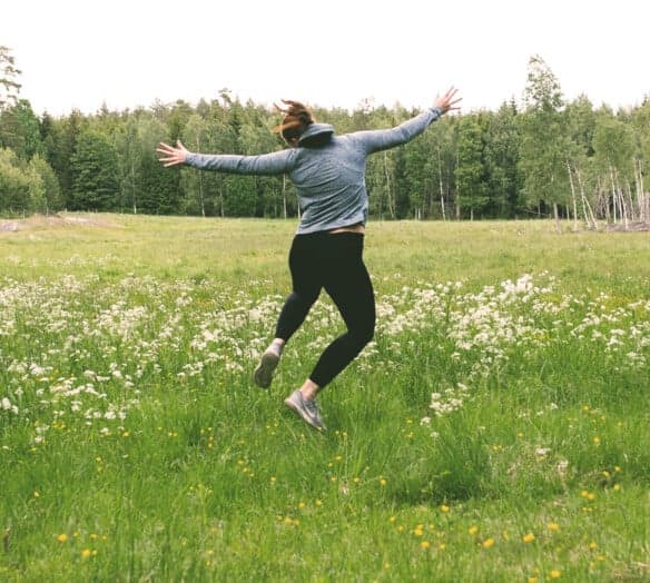 Kvinna hoppar på äng